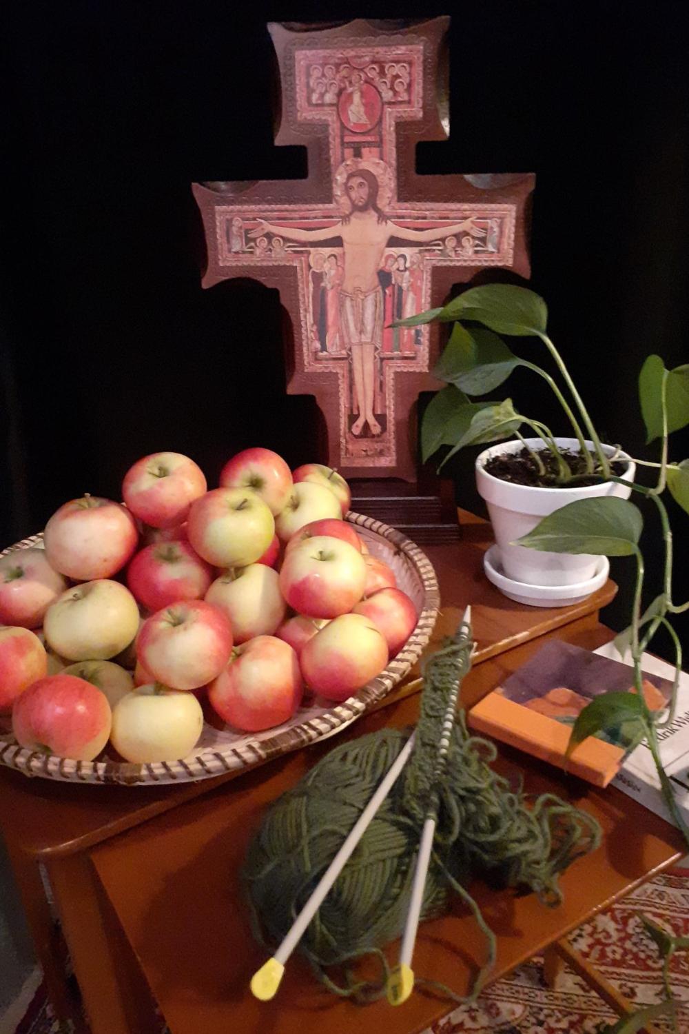 Pöydällä risti, omenoita, kutimet, kukka